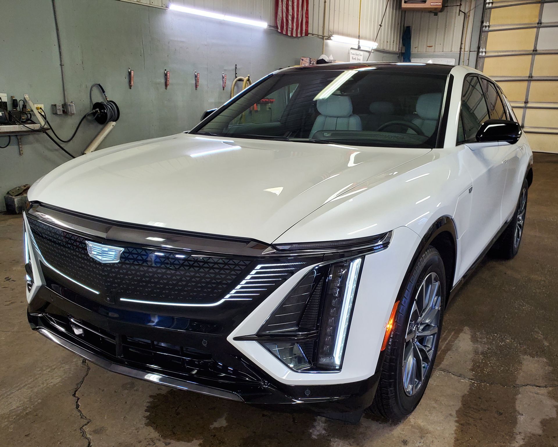 A white car is parked in a garage next to a garage door.