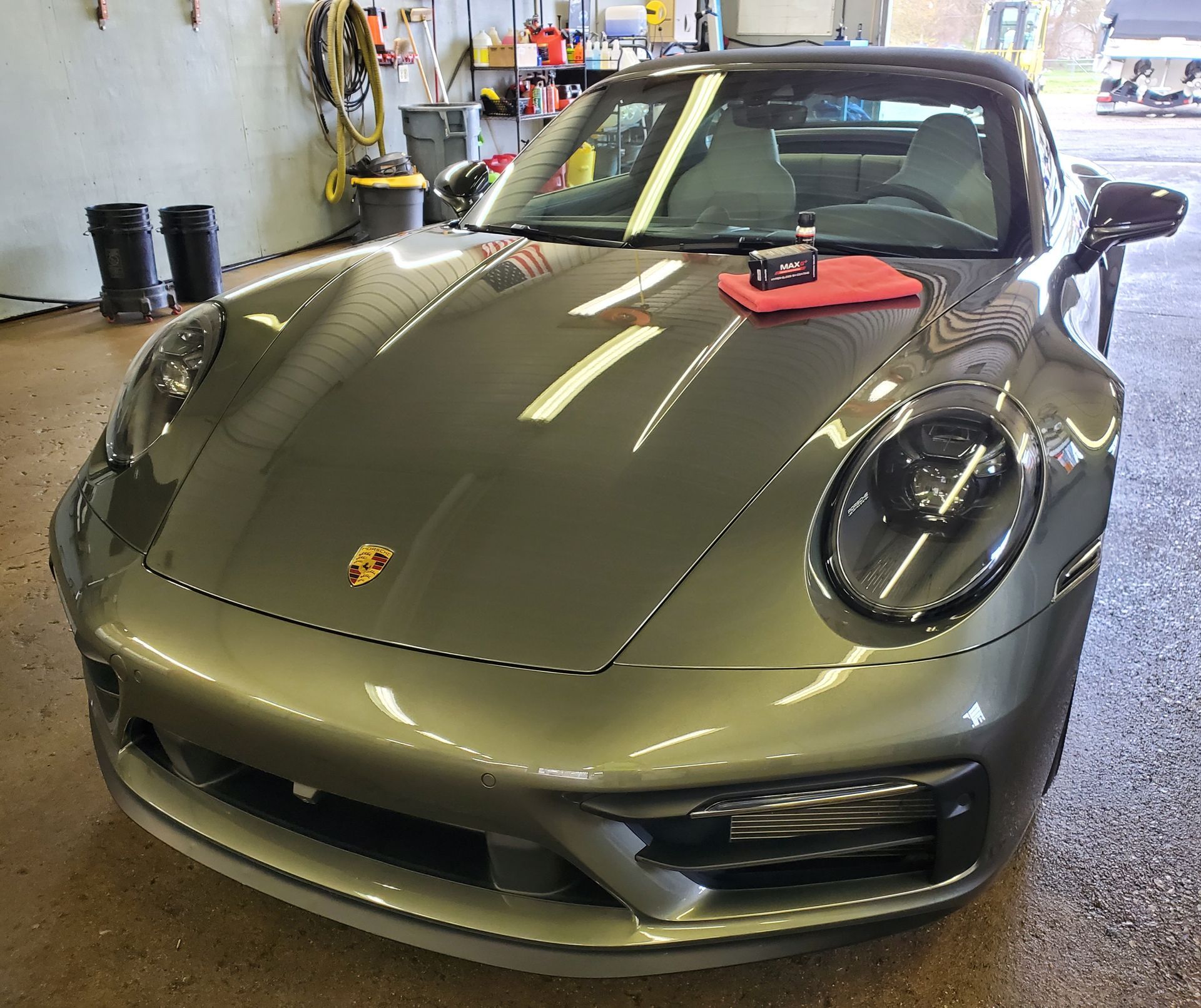 A gray porsche 911 is parked in a garage.