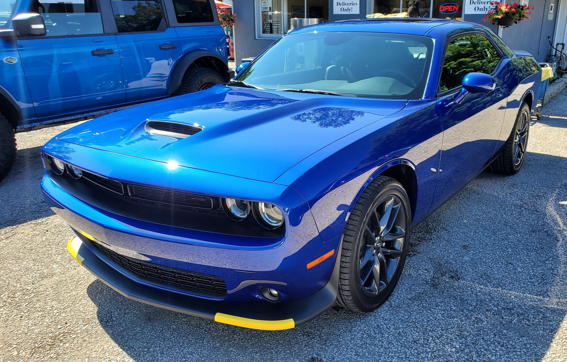 A blue dodge challenger is parked in a gravel lot.