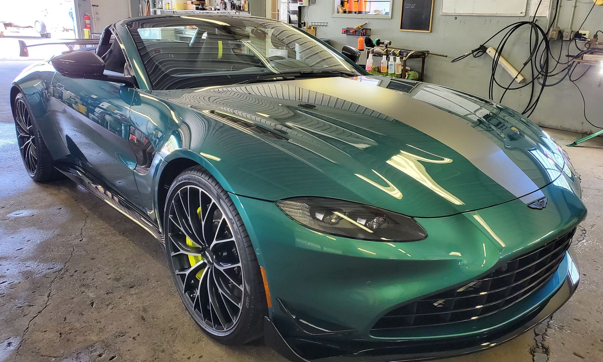 A green sports car is parked in a garage.