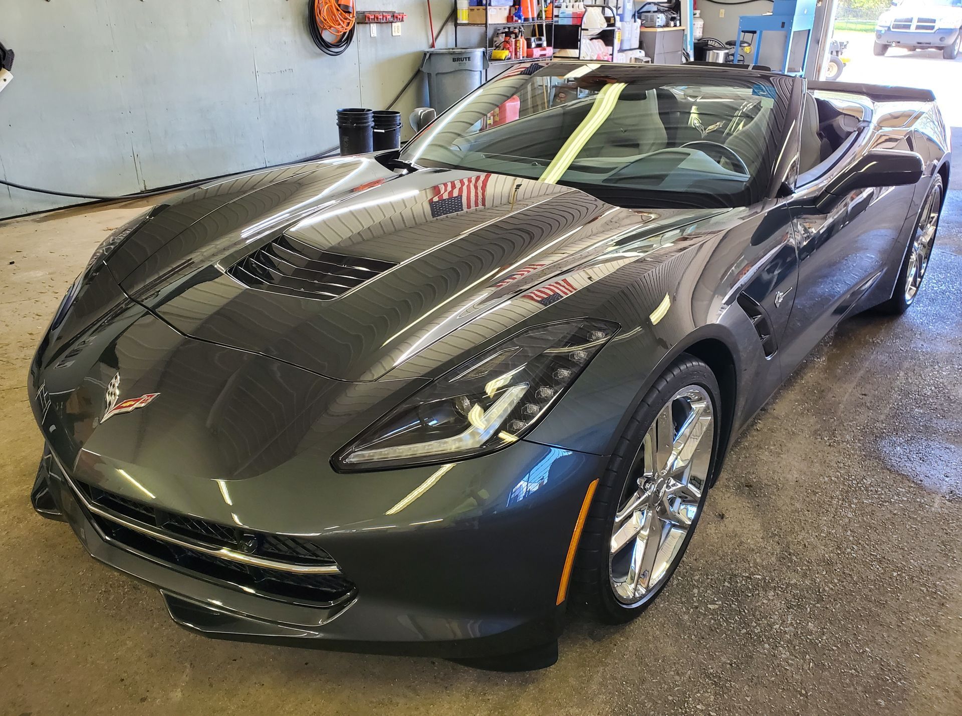 A gray corvette convertible is parked in a garage.