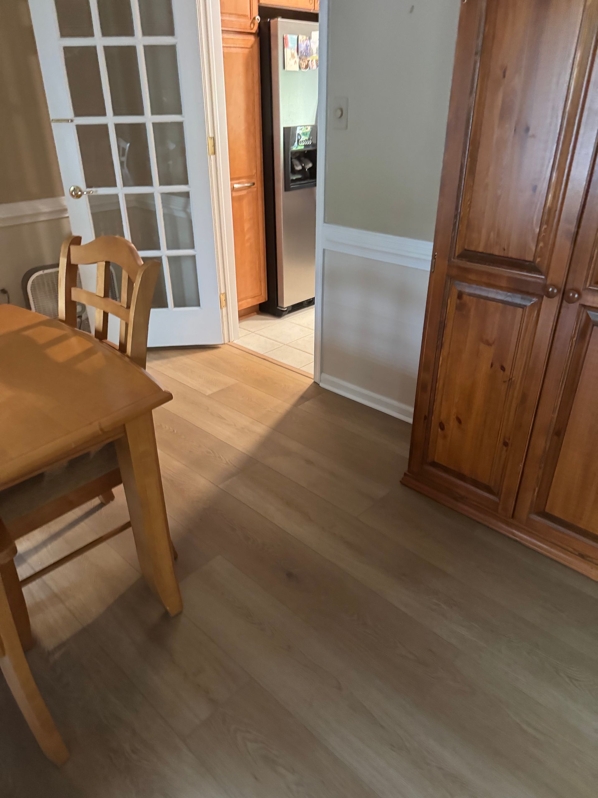 Dining room with wooden table and cabinet, French doors, and an open doorway into a hallway.
