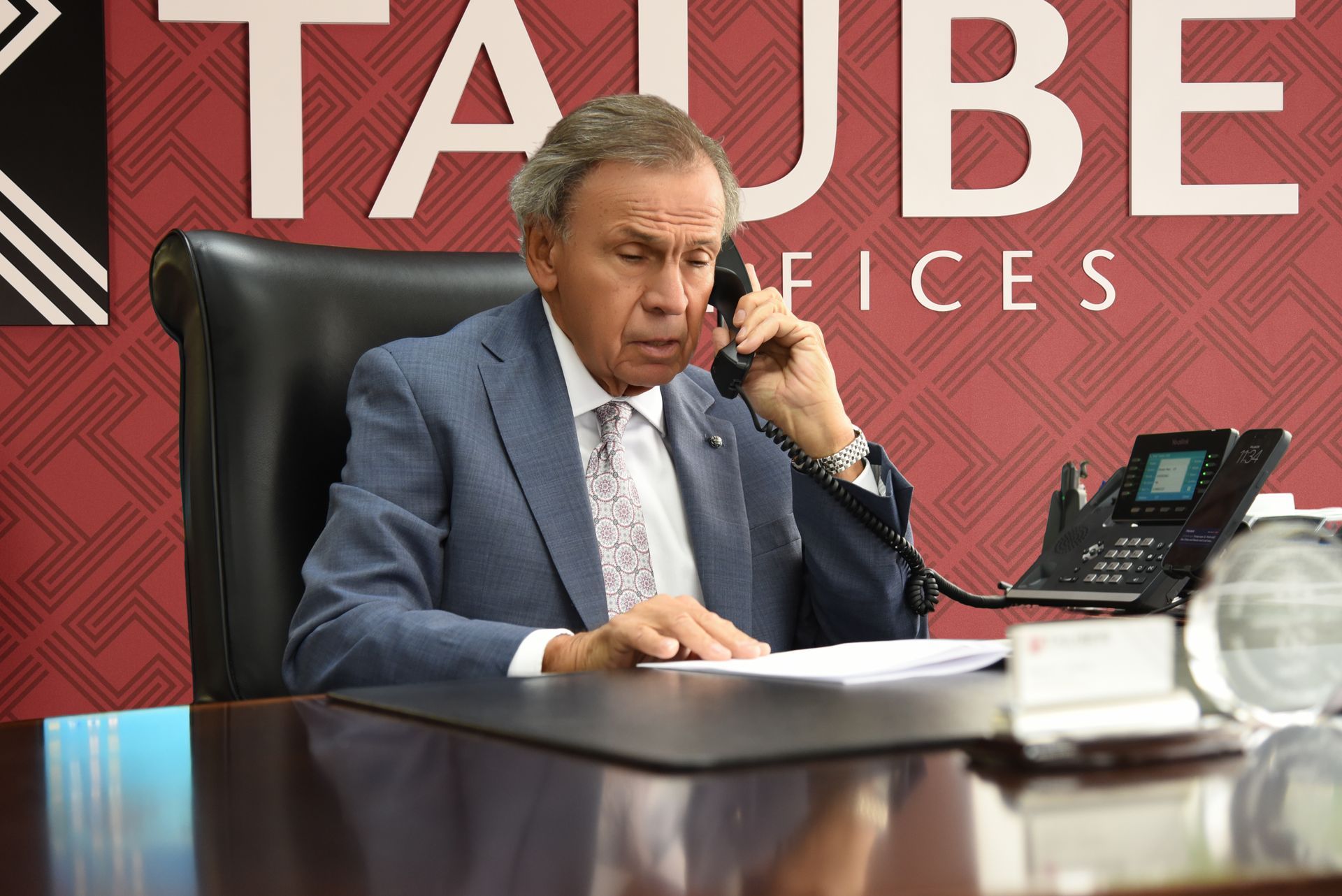 Portrait of a suited man seated in an office, with the Tauber Law Offices logo below