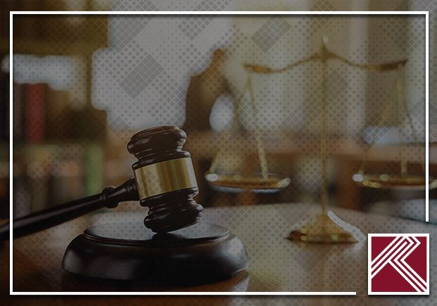 Judge’s gavel on a desk with a blurred scales-of-justice background and a law logo in the corner