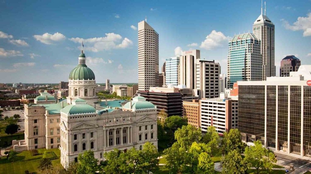 City skyline with a historic domed building in the foreground and modern high-rises under a clear blue sky.