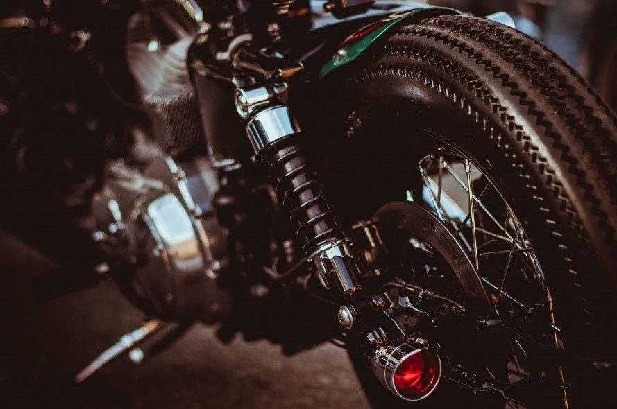 Close-up of a vintage motorcycle rear wheel and suspension in warm, low light