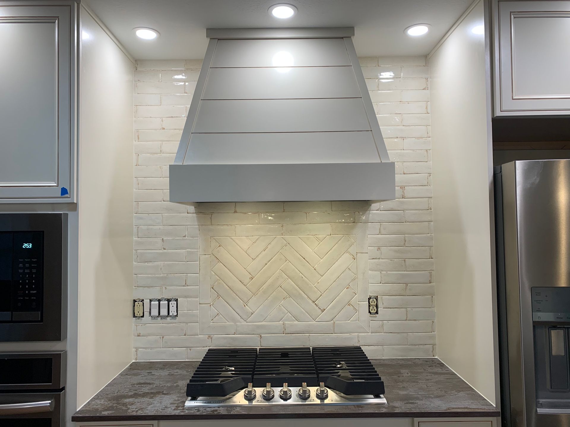 a kitchen with a stove-top oven and a stainless steel refrigerator