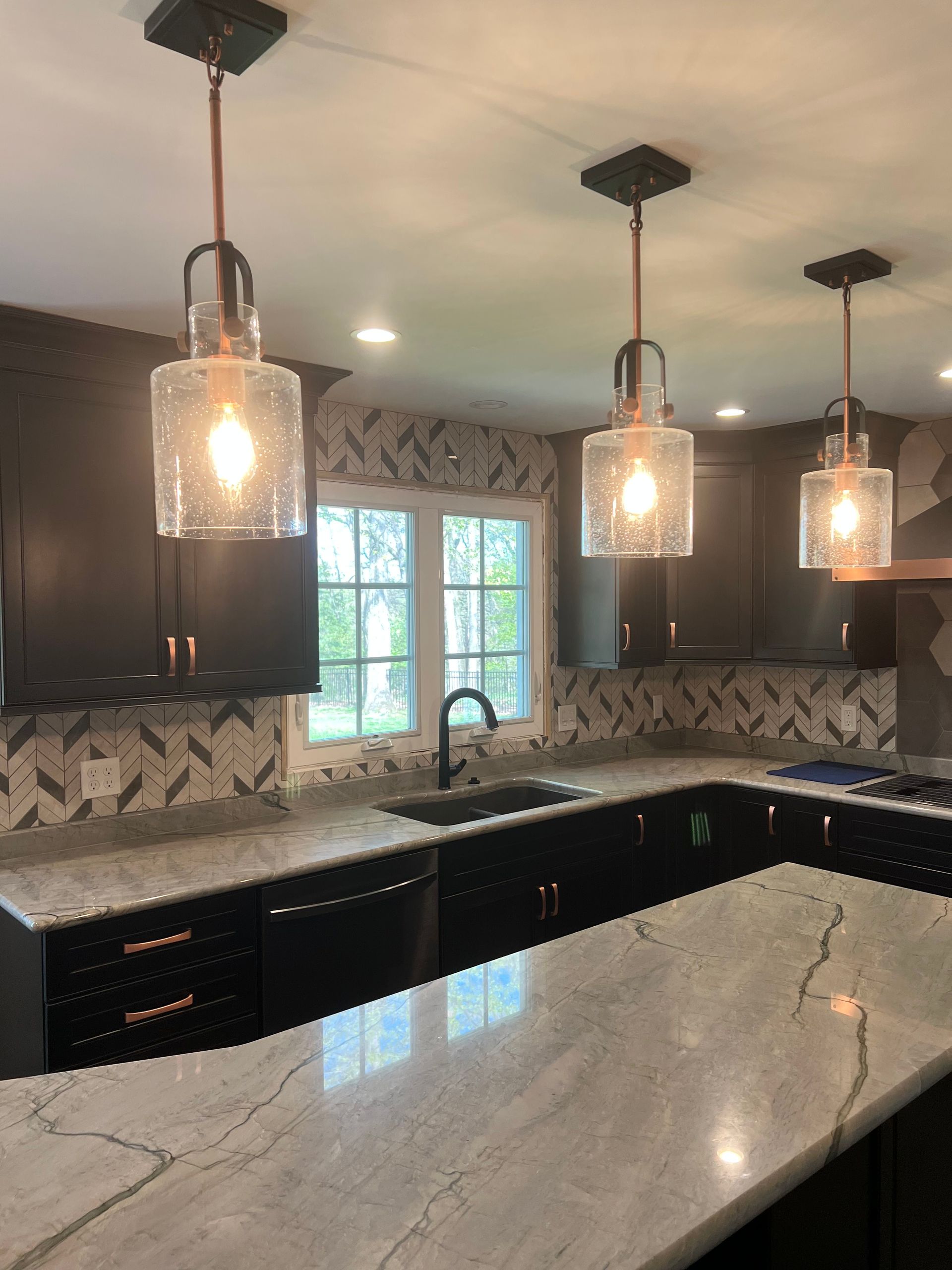 a kitchen with a marble counter top and black cabinets