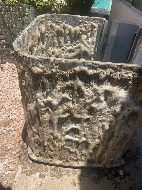 A weathered, textured, gray and beige container outdoors, possibly concrete.