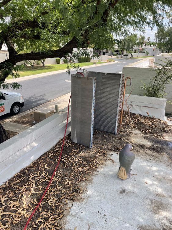 AC condenser units sit next to a street. A tree provides shade, with a work truck nearby.