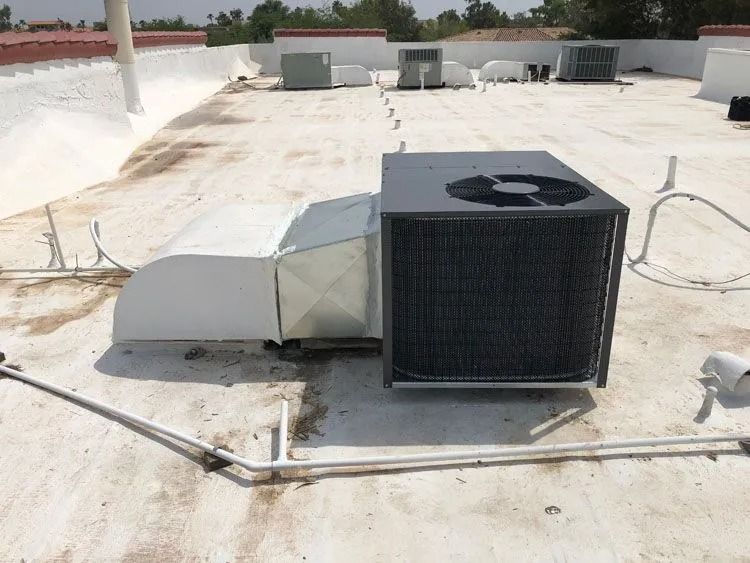 HVAC unit on a white commercial rooftop, with other units and equipment visible.