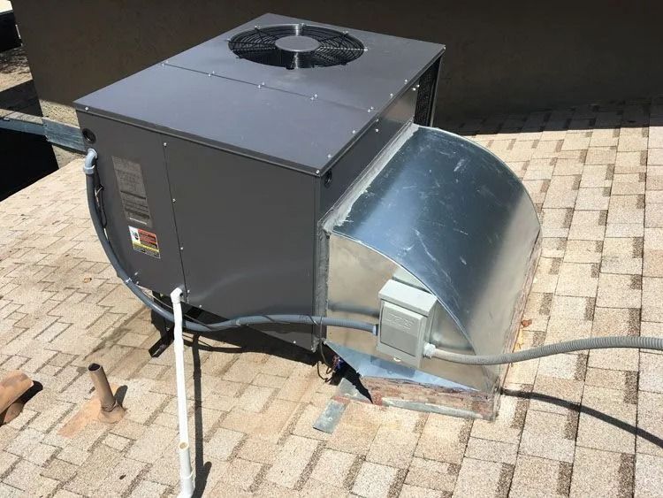 A gray rooftop HVAC unit with a fan and ductwork.