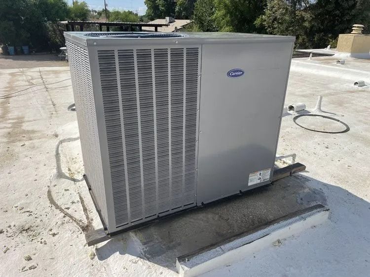 Gray Carrier AC unit on a rooftop with a white reflective coating.