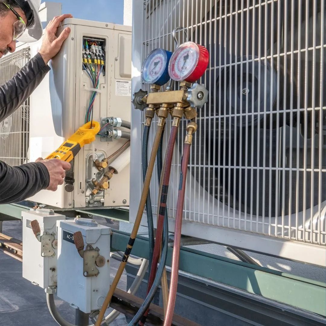 HVAC technician using gauges on an air conditioning unit; outdoors, sunny day.