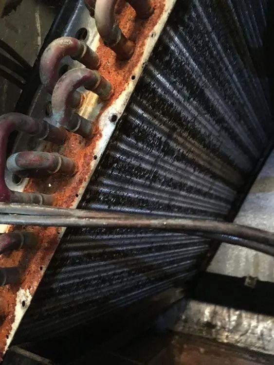 Rusty, dirty HVAC evaporator coil with refrigerant lines.