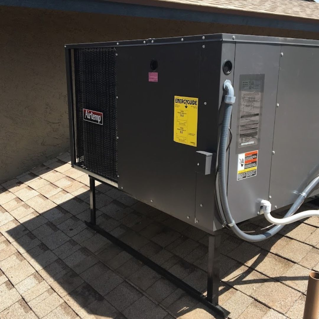 Dark-colored HVAC unit on a rooftop, with a yellow energy guide label and black metal supports.