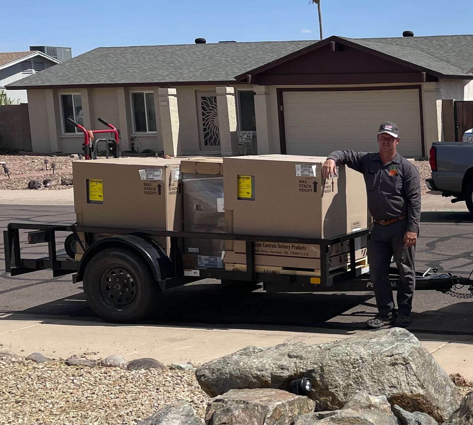 Man standing by trailer loaded with boxes in front of a house.