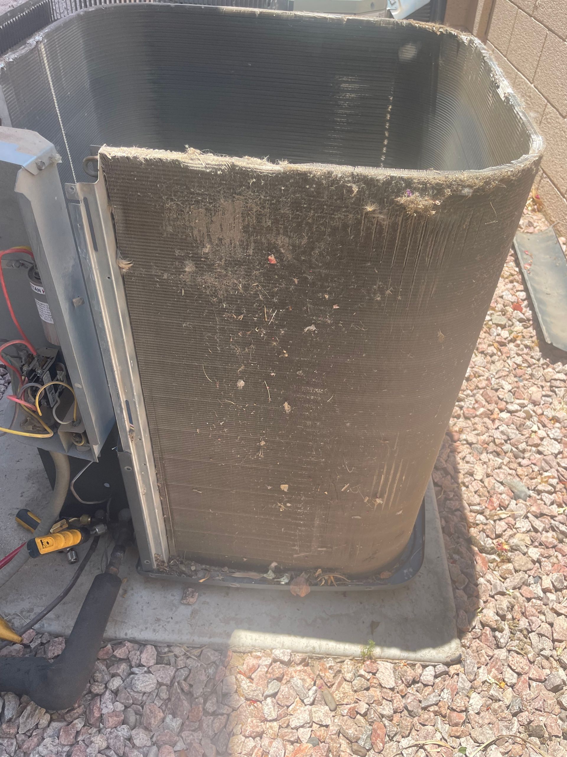 Dirty outdoor air conditioning unit's coil; covered in debris and dirt, sits on concrete.