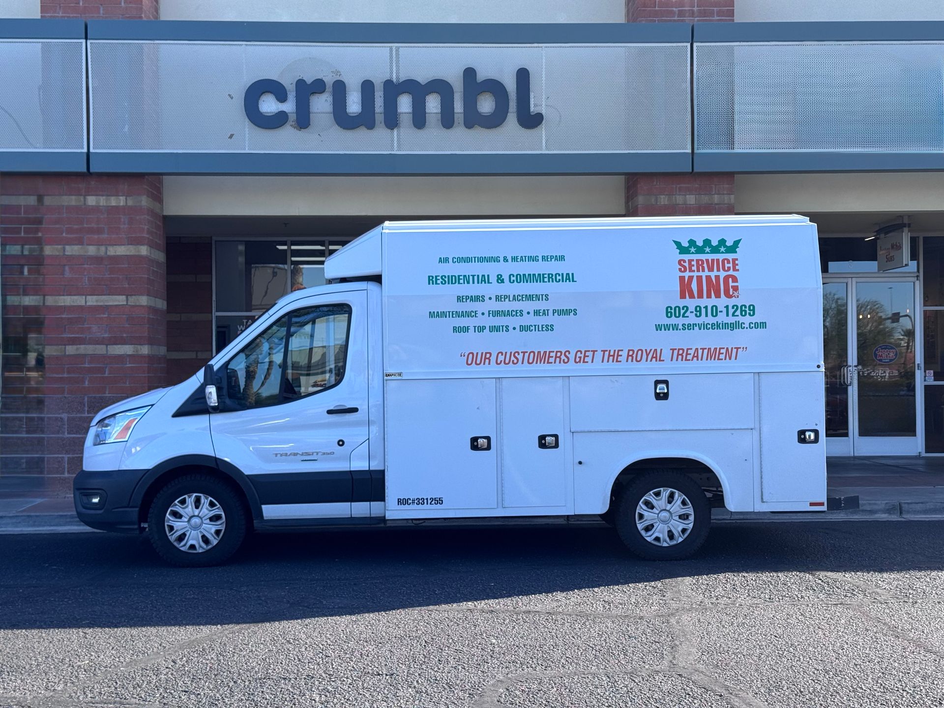 White delivery van parked outside a Crumbl Cookies store. The van is labeled 