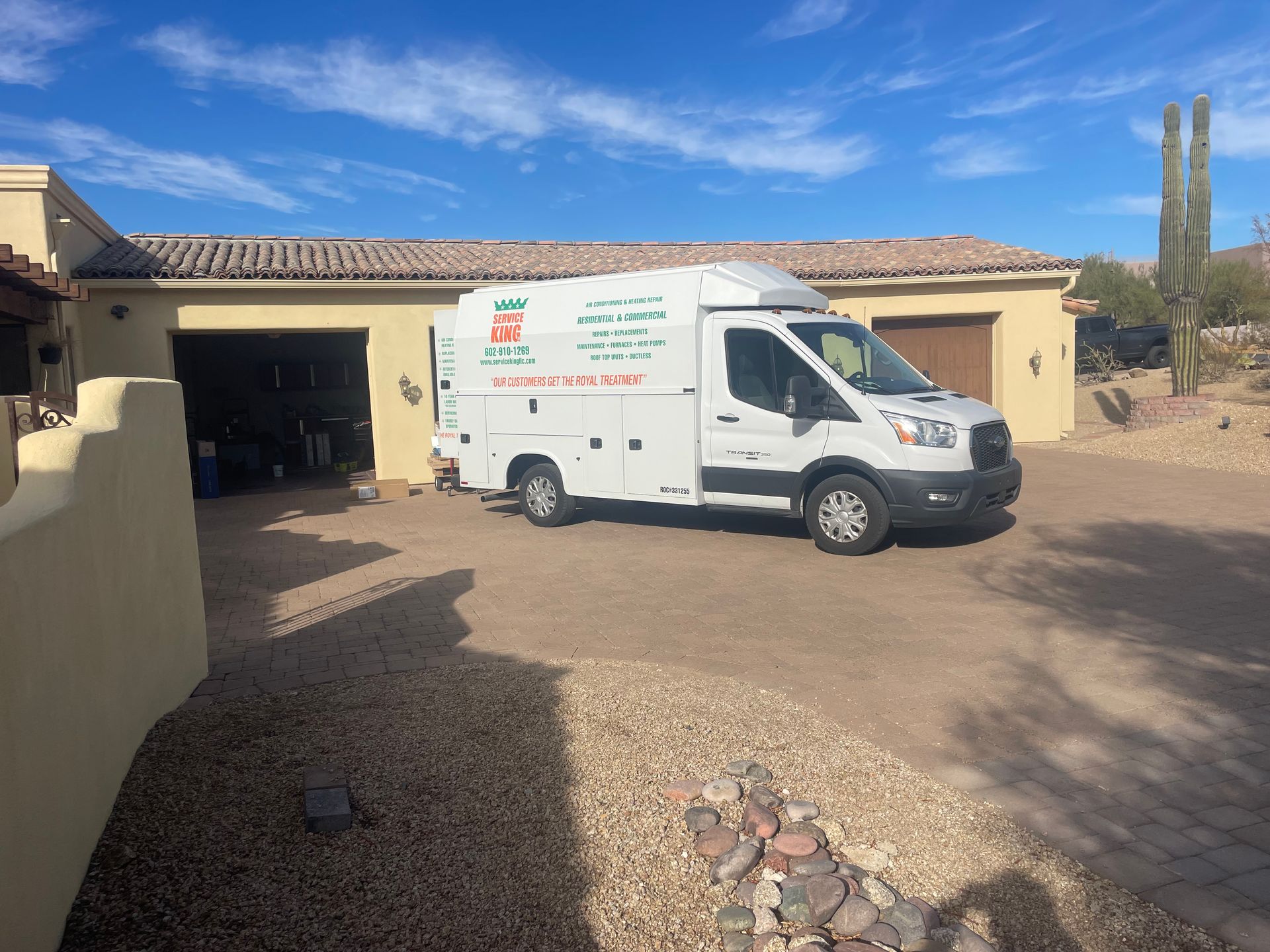 White service van parked in a driveway in front of a tan garage on a sunny day.