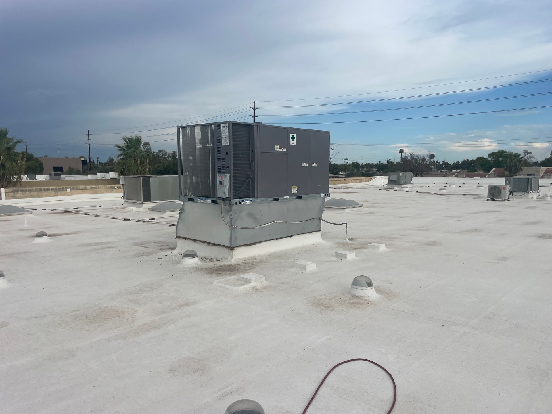 HVAC unit on a white roof, overcast sky.