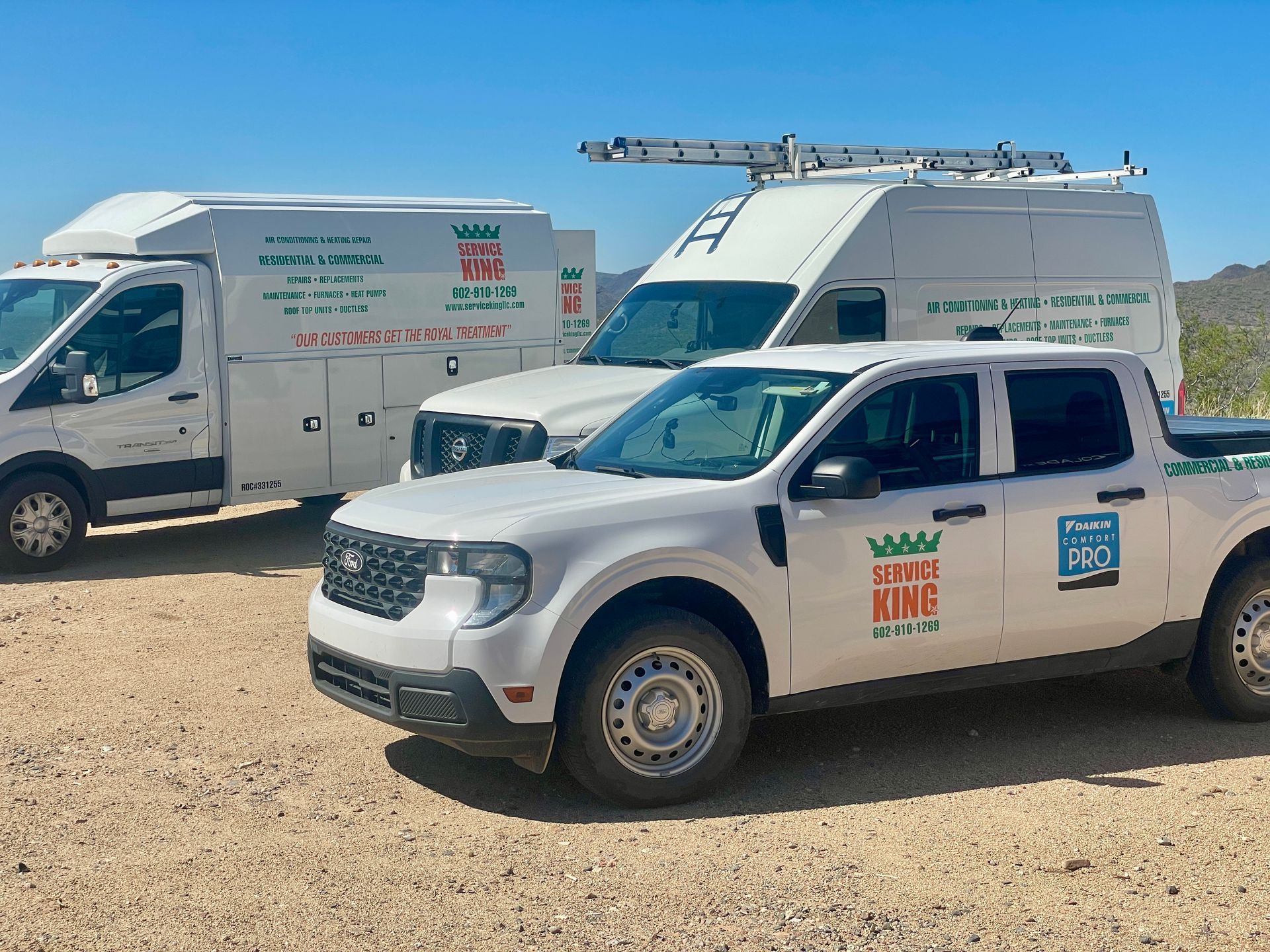 White service trucks with company logo parked outdoors on dirt.