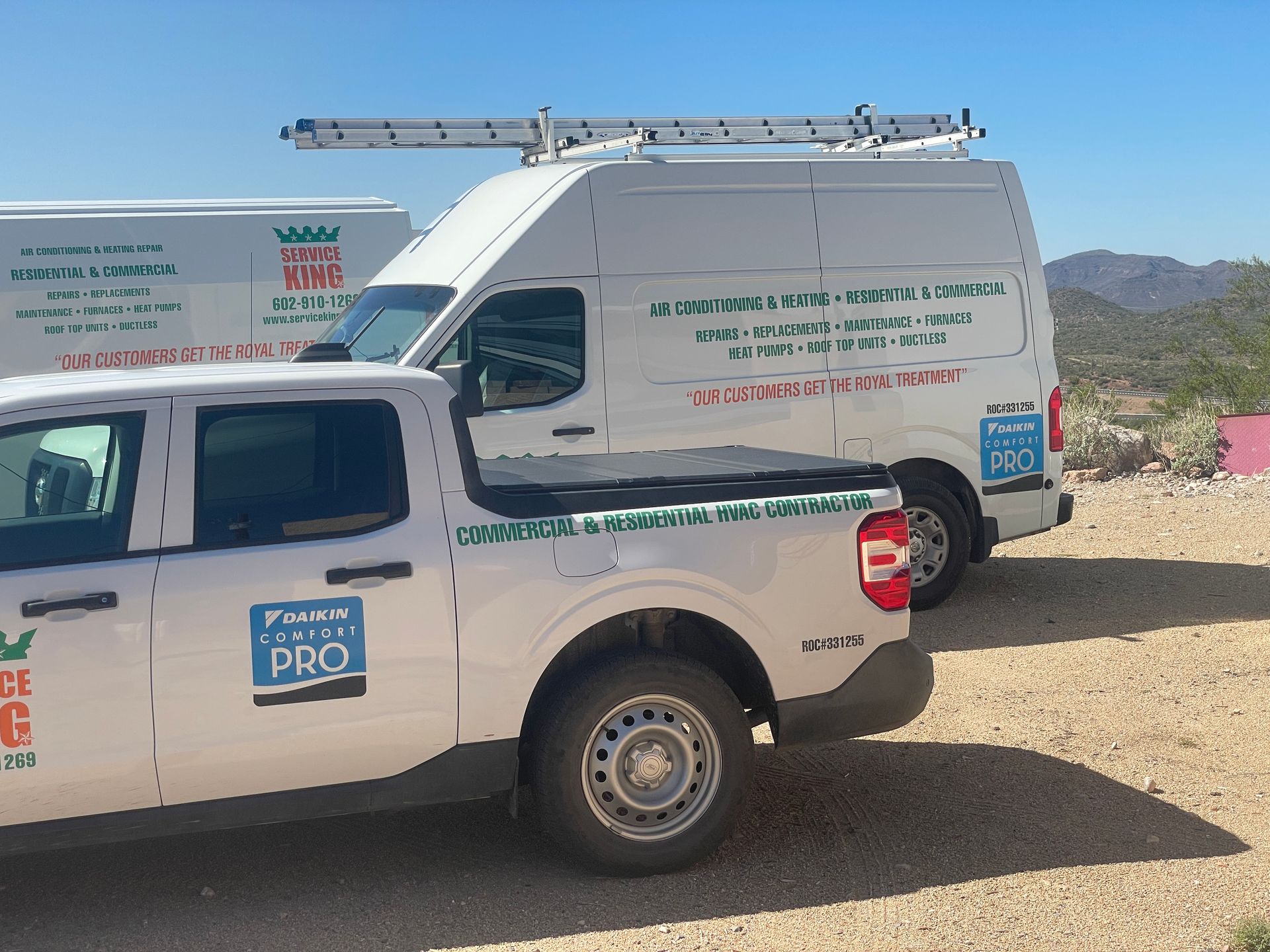 White work vans and a pickup truck with company logo parked outdoors in sunny setting.