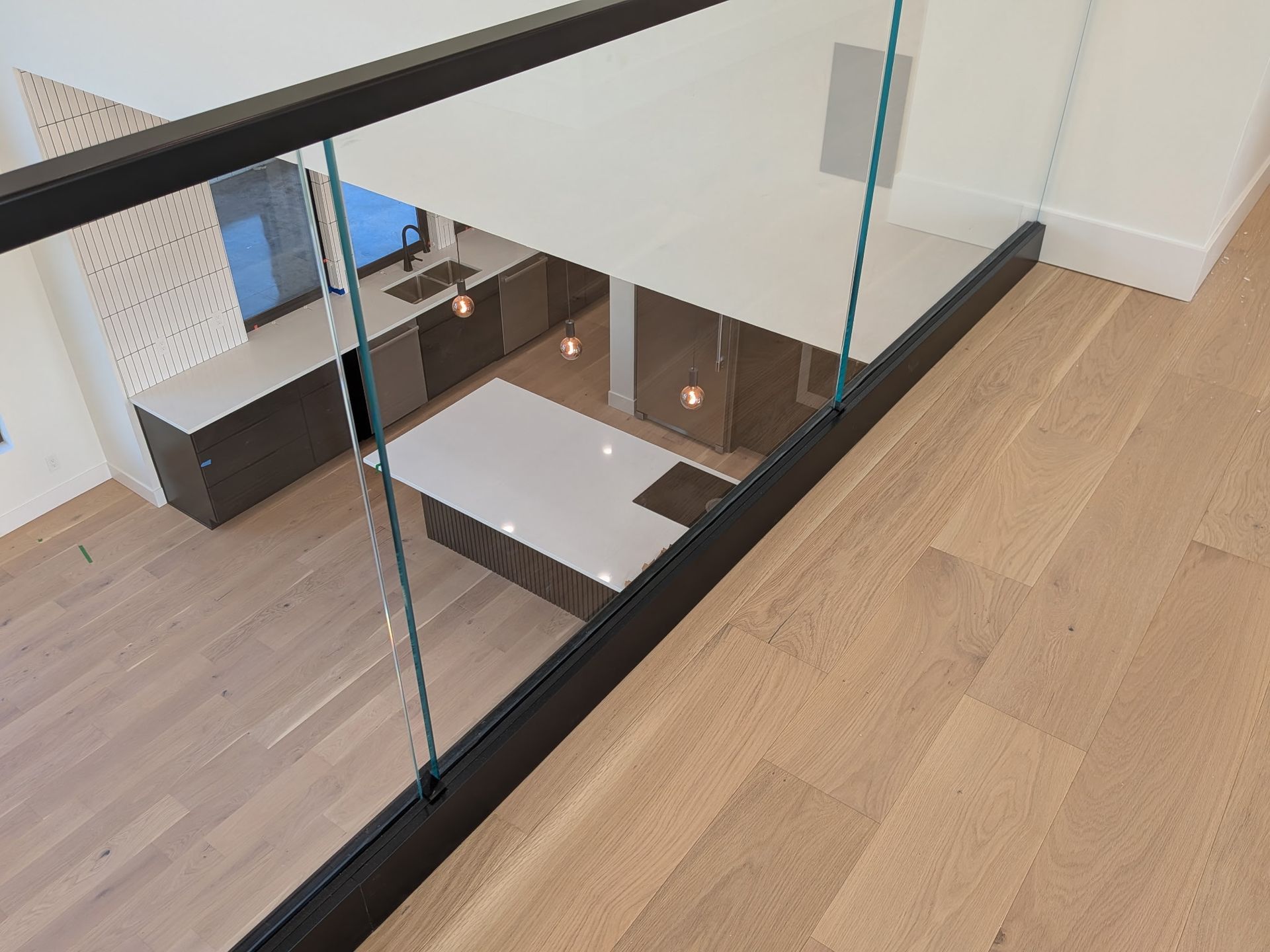 View from above, a kitchen with a white island and wooden floors, glass railing.