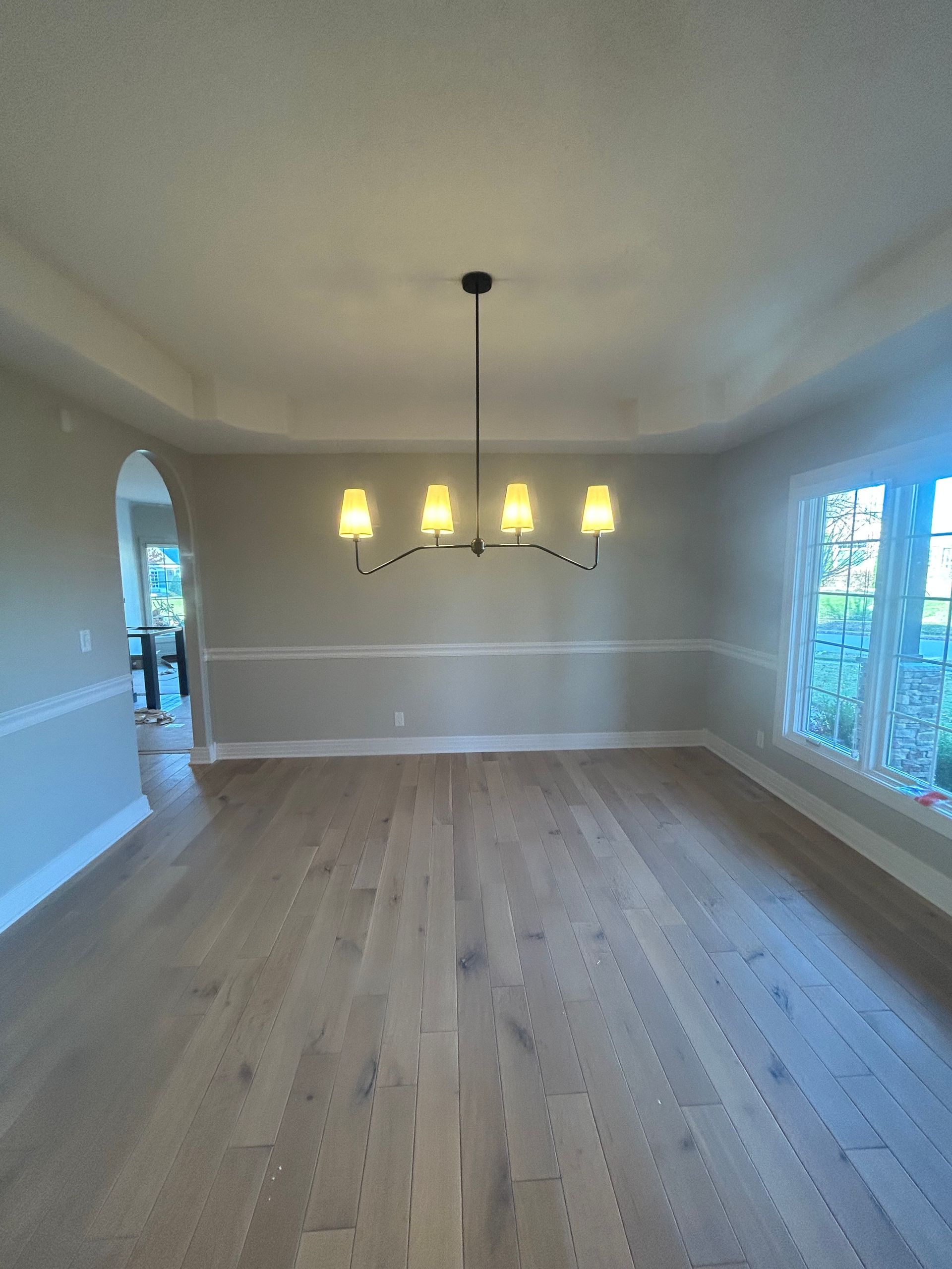 Empty dining room with chandelier, light wood floors, and neutral walls.