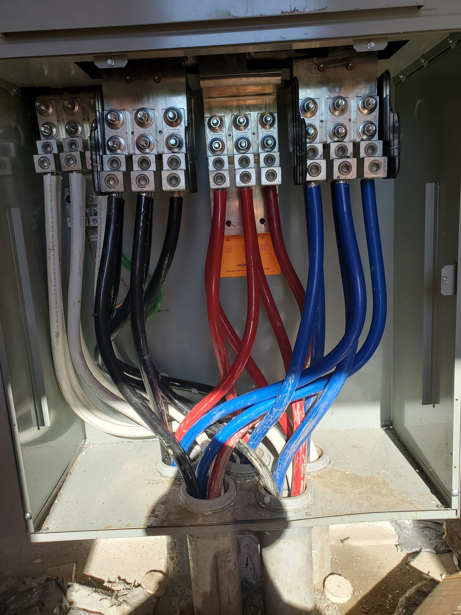 Electrical wiring in a metal enclosure. Blue, red, black, and white wires connected to terminals.