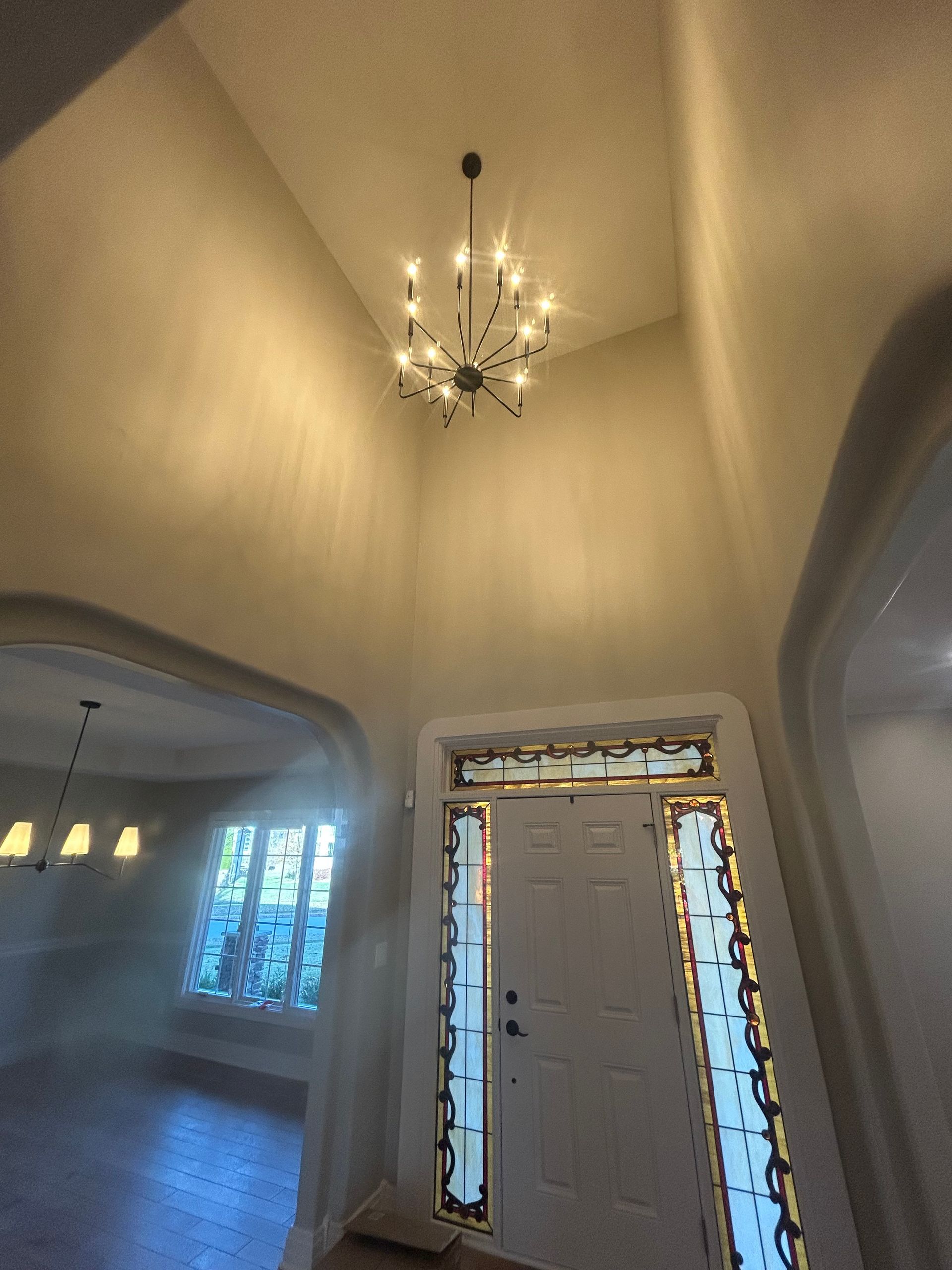 Entryway with high ceiling, chandelier, front door with sidelights, and arched doorways.
