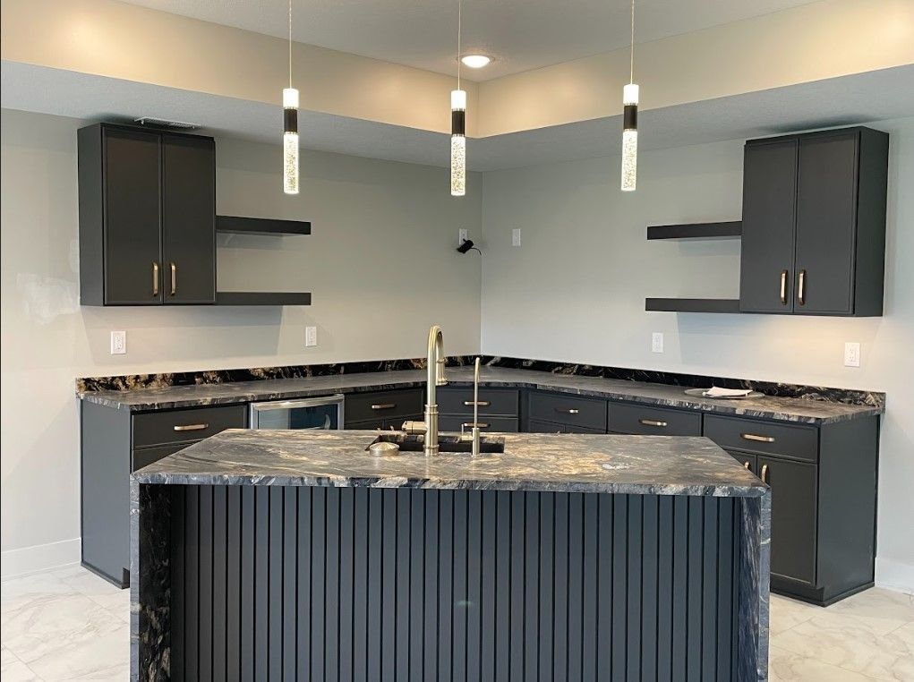 Modern kitchen with black cabinets, island, and countertops, gold fixtures, and pendant lights.