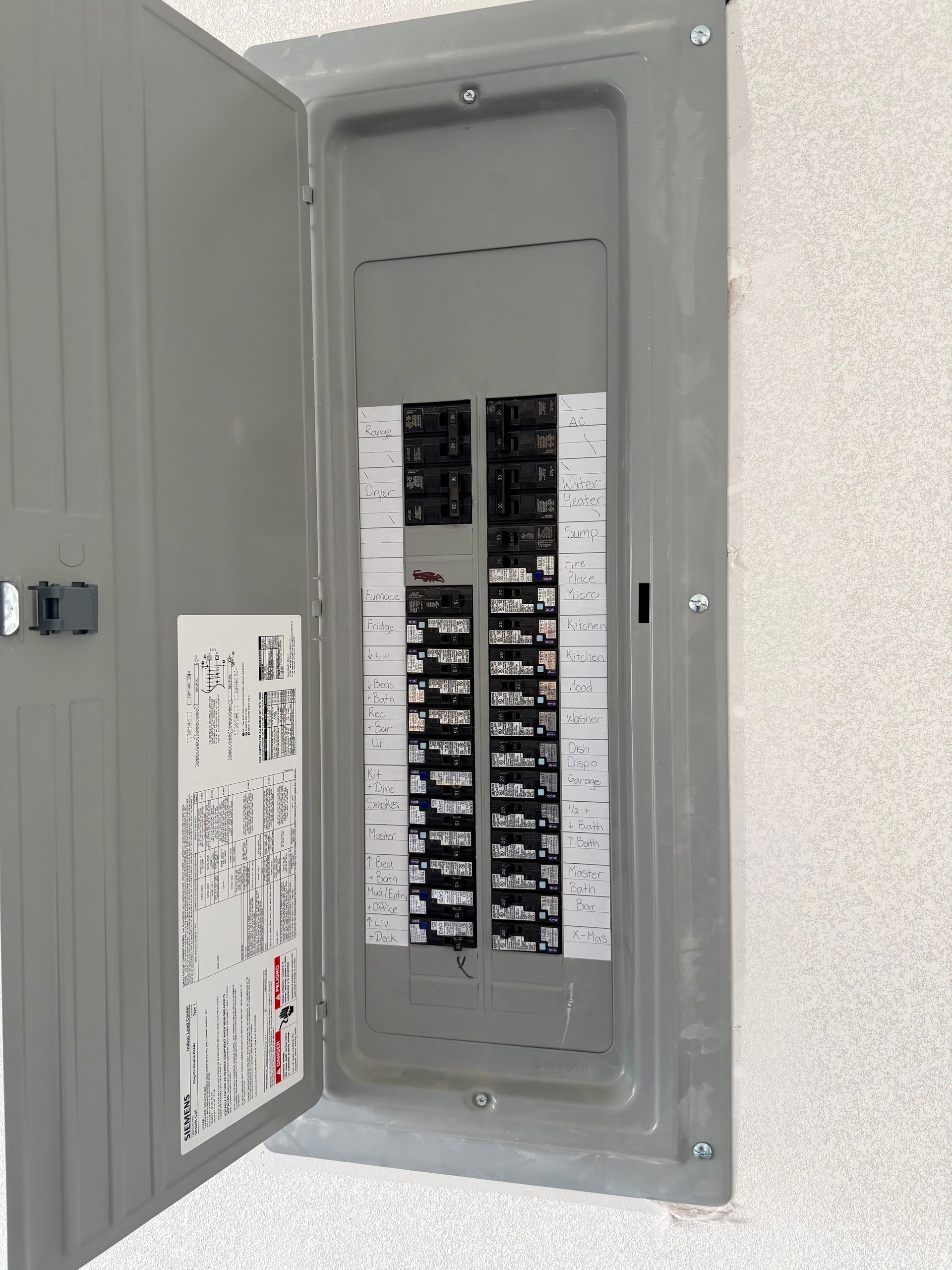 Open gray electrical panel on a stucco wall. Breaker switches are visible.