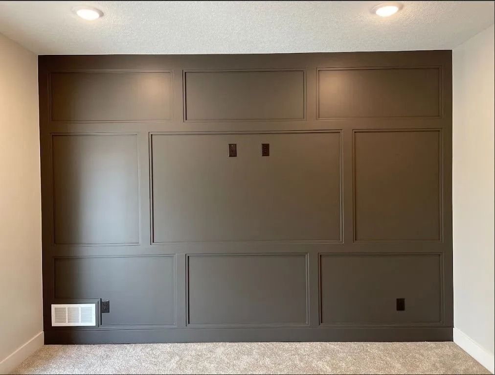 Dark gray paneled accent wall with recessed lighting, electrical outlets, and a small vent.