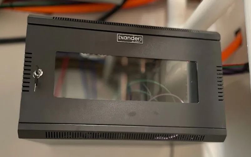 Black wall-mounted network rack cabinet with a glass door and key.