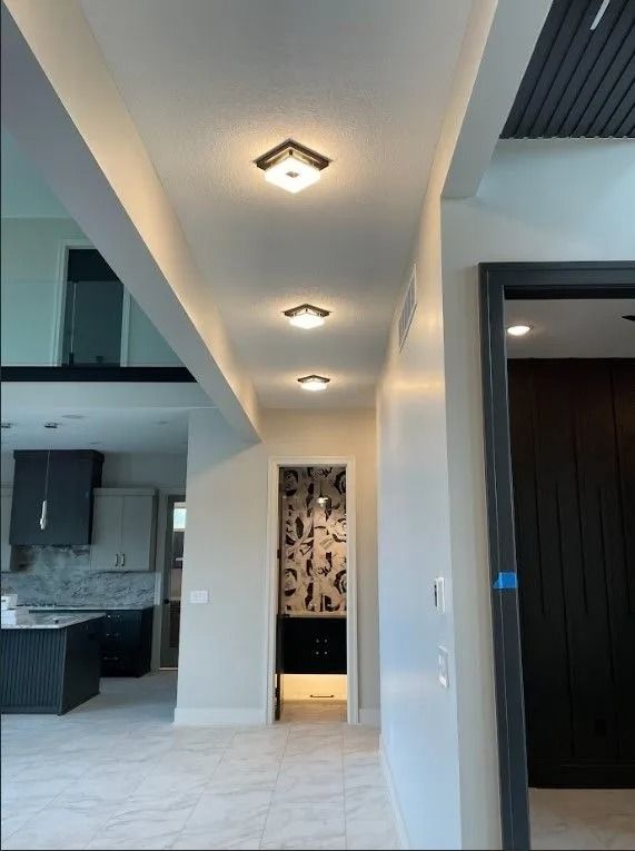 Hallway with recessed ceiling lights; open to kitchen and a doorway.