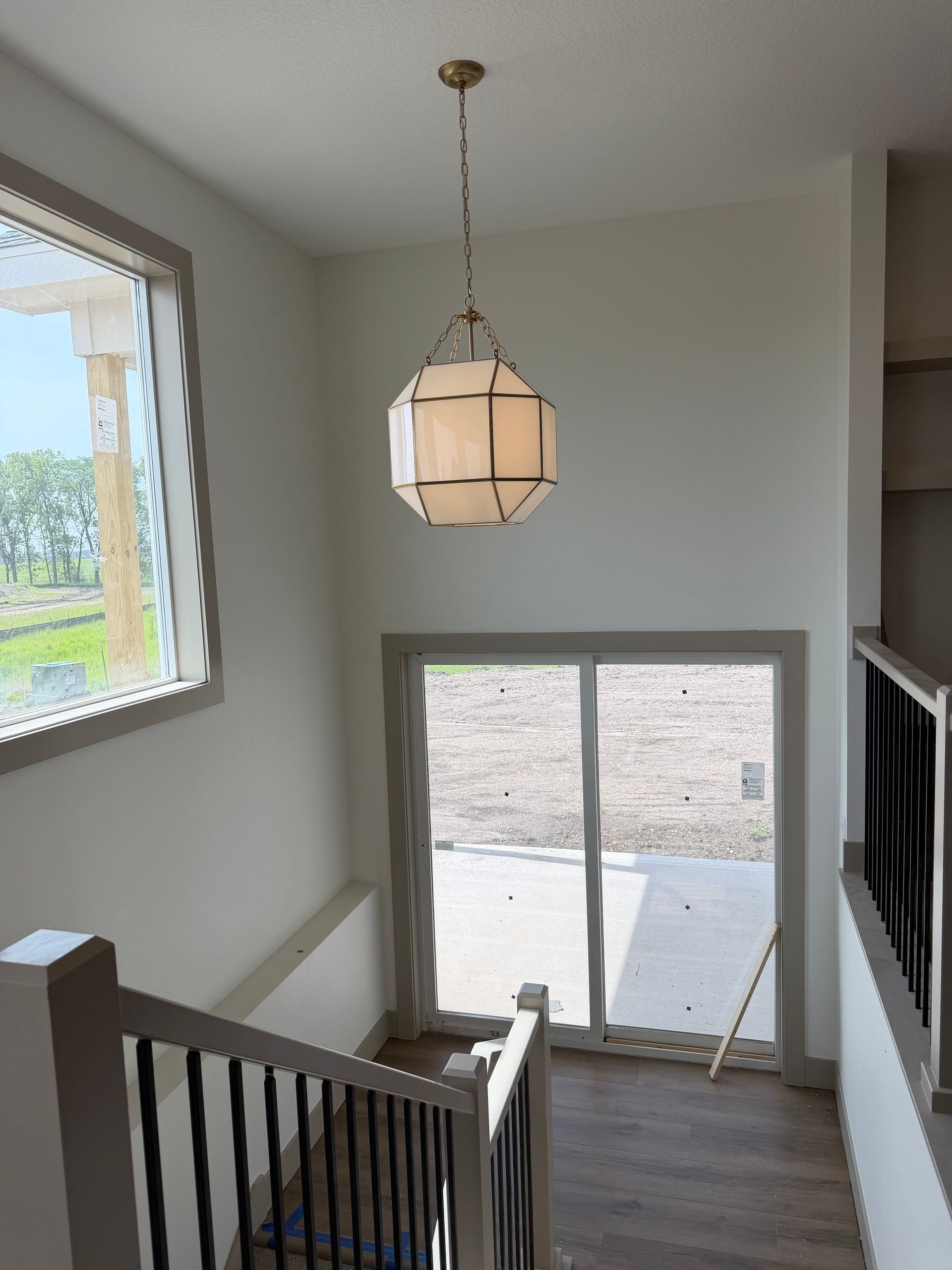 Staircase landing with hanging light, window, and glass doors opening to a patio.
