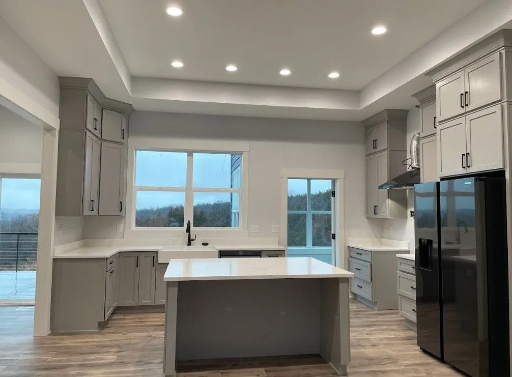 Modern kitchen with gray cabinets, white countertops, and black appliances.