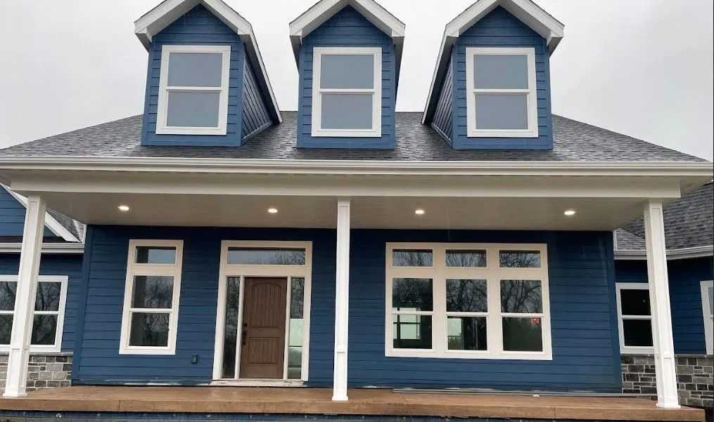 Blue house with white trim, three dormer windows, and covered porch.