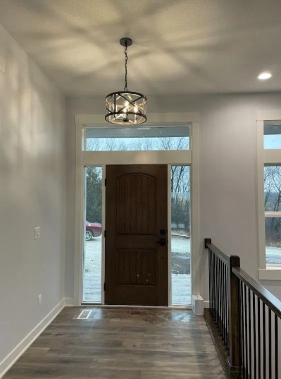 Hallway with a wooden door, windows, and a chandelier.