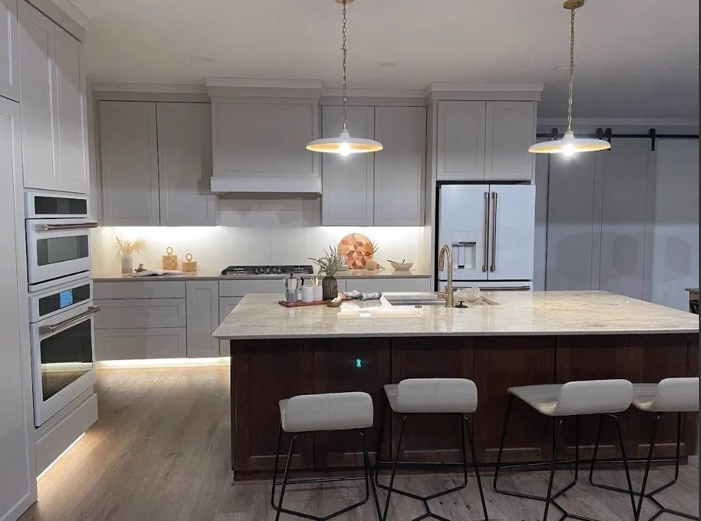 Modern kitchen with island, cabinets, appliances, pendant lights, and bar stools.