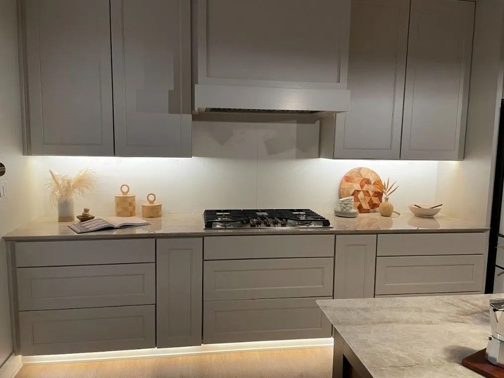 Gray kitchen cabinets and countertops with stovetop and range hood.