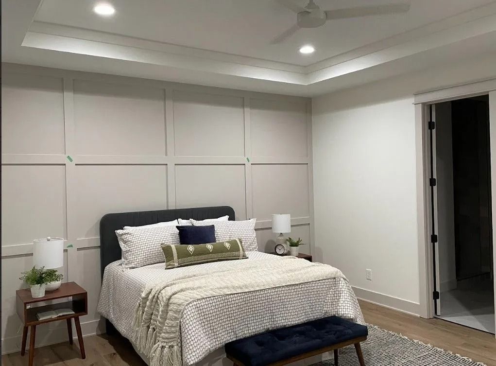 Bedroom with gray paneling, bed, nightstands, and sliding door.