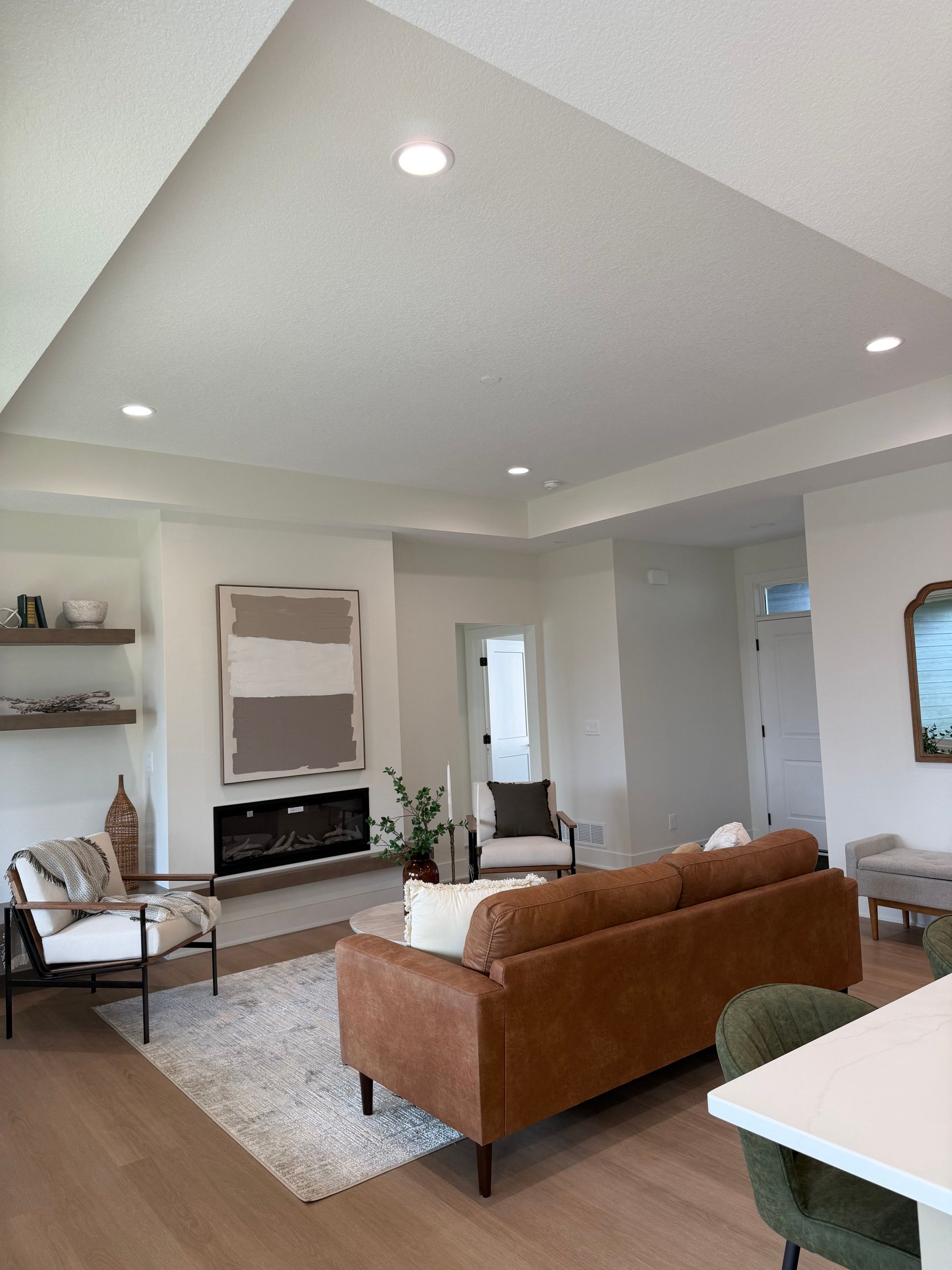 Living room with brown leather sofa, fireplace, and modern artwork. White walls and ceiling.
