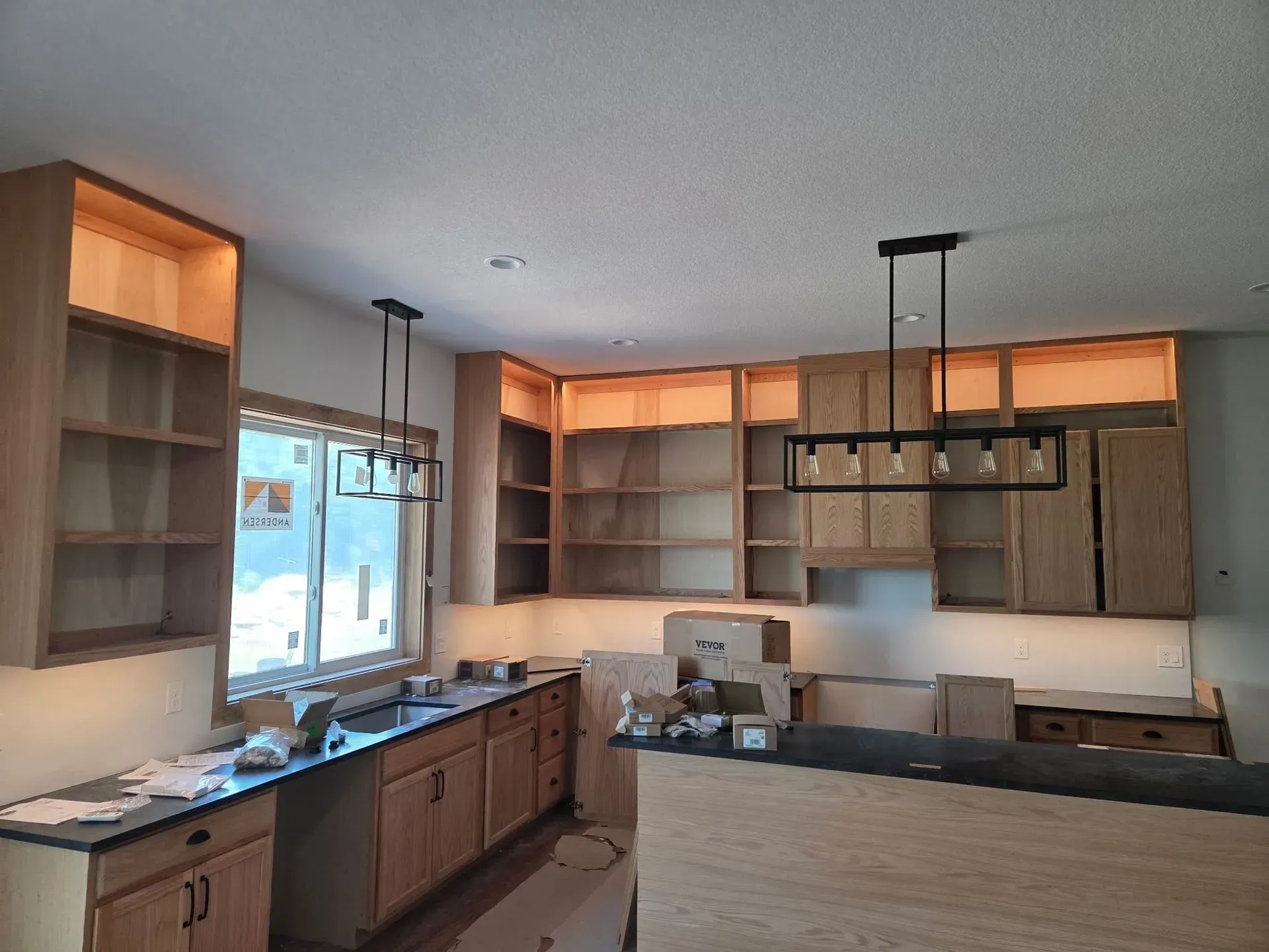 Modern kitchen with wood cabinets, island, and large windows under warm lighting