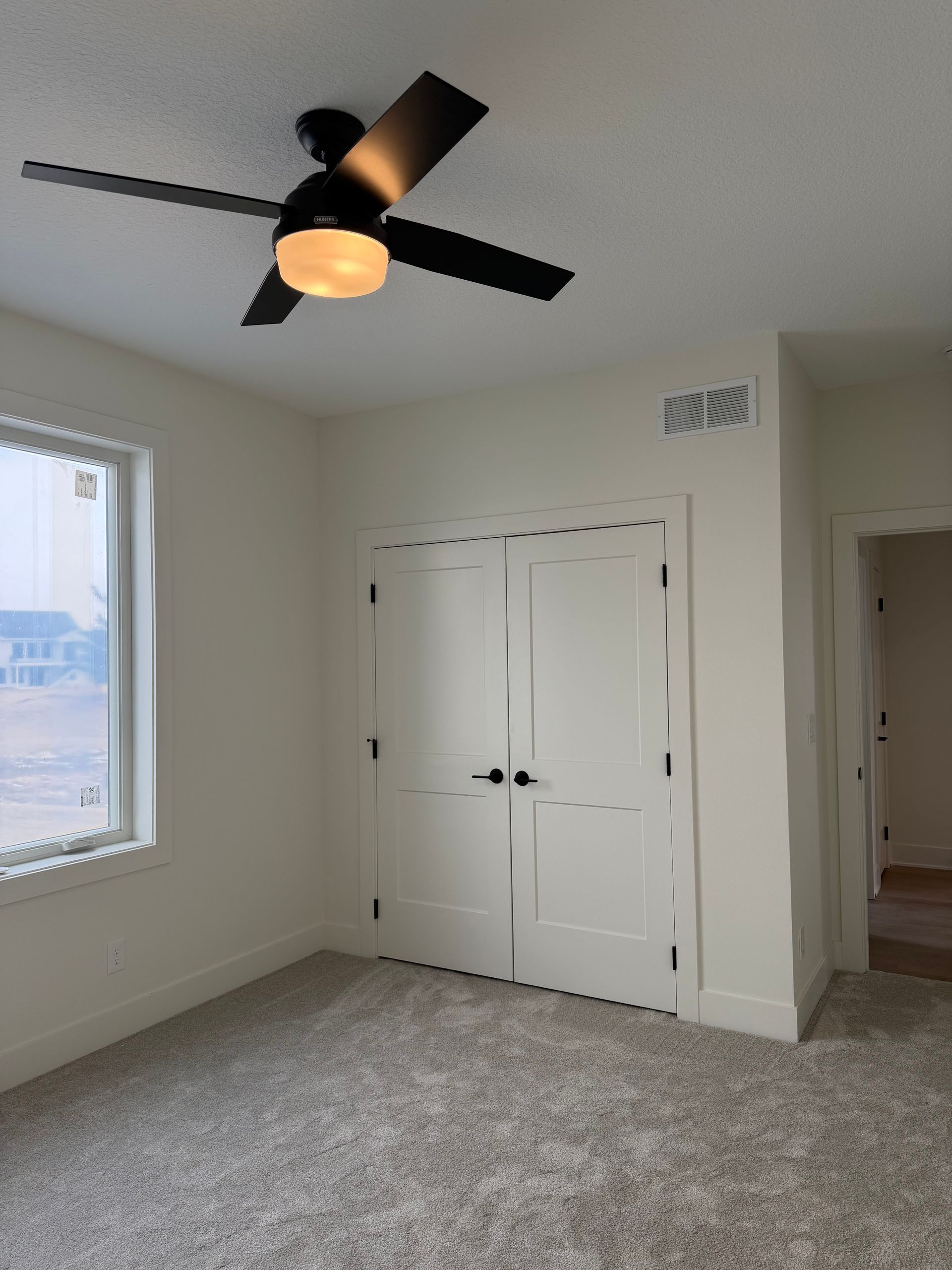 Bedroom with white walls, a closet, a window, and a ceiling fan.