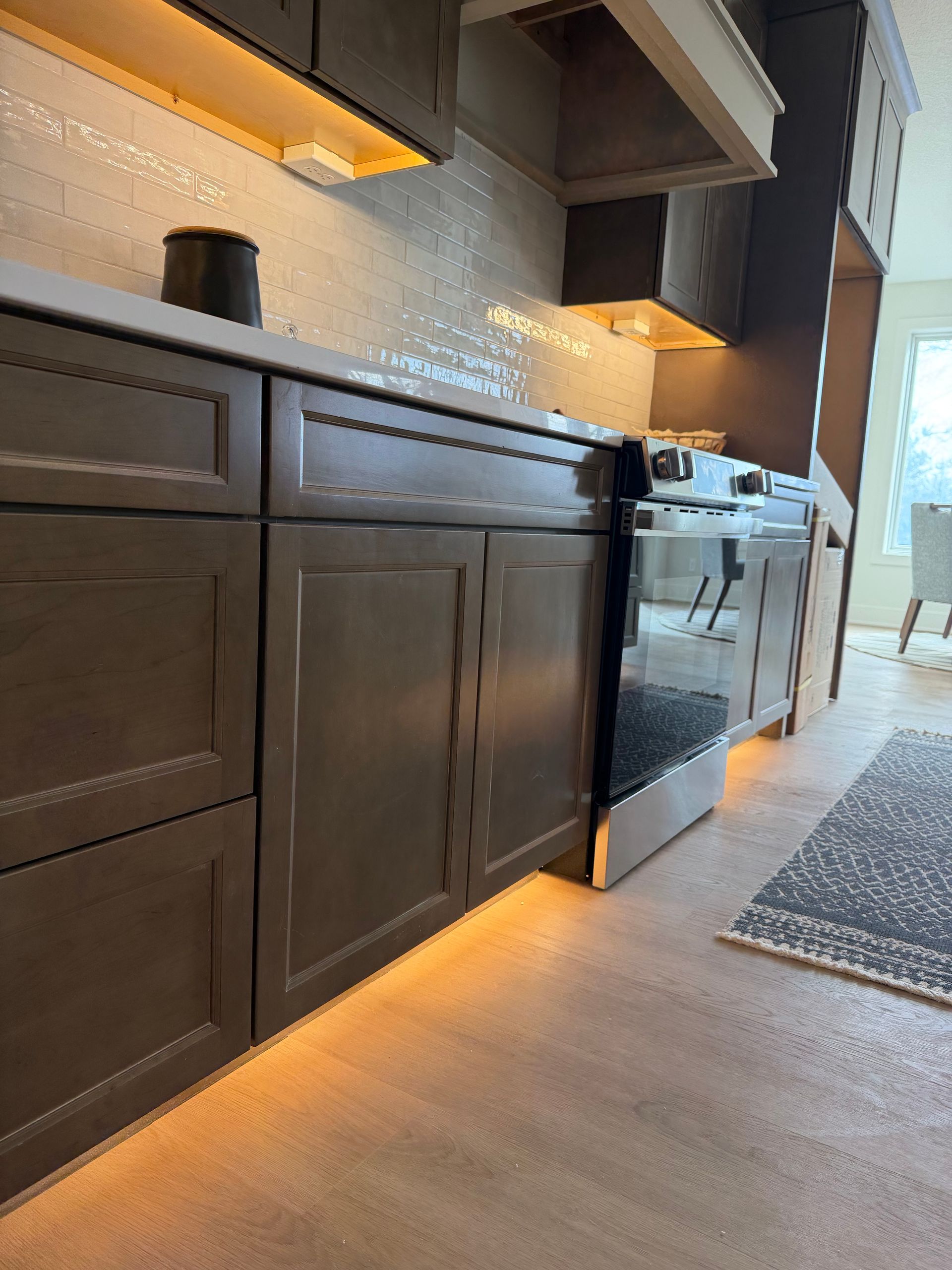 Kitchen cabinets with under-cabinet lighting, a stove, and a decorative backsplash.