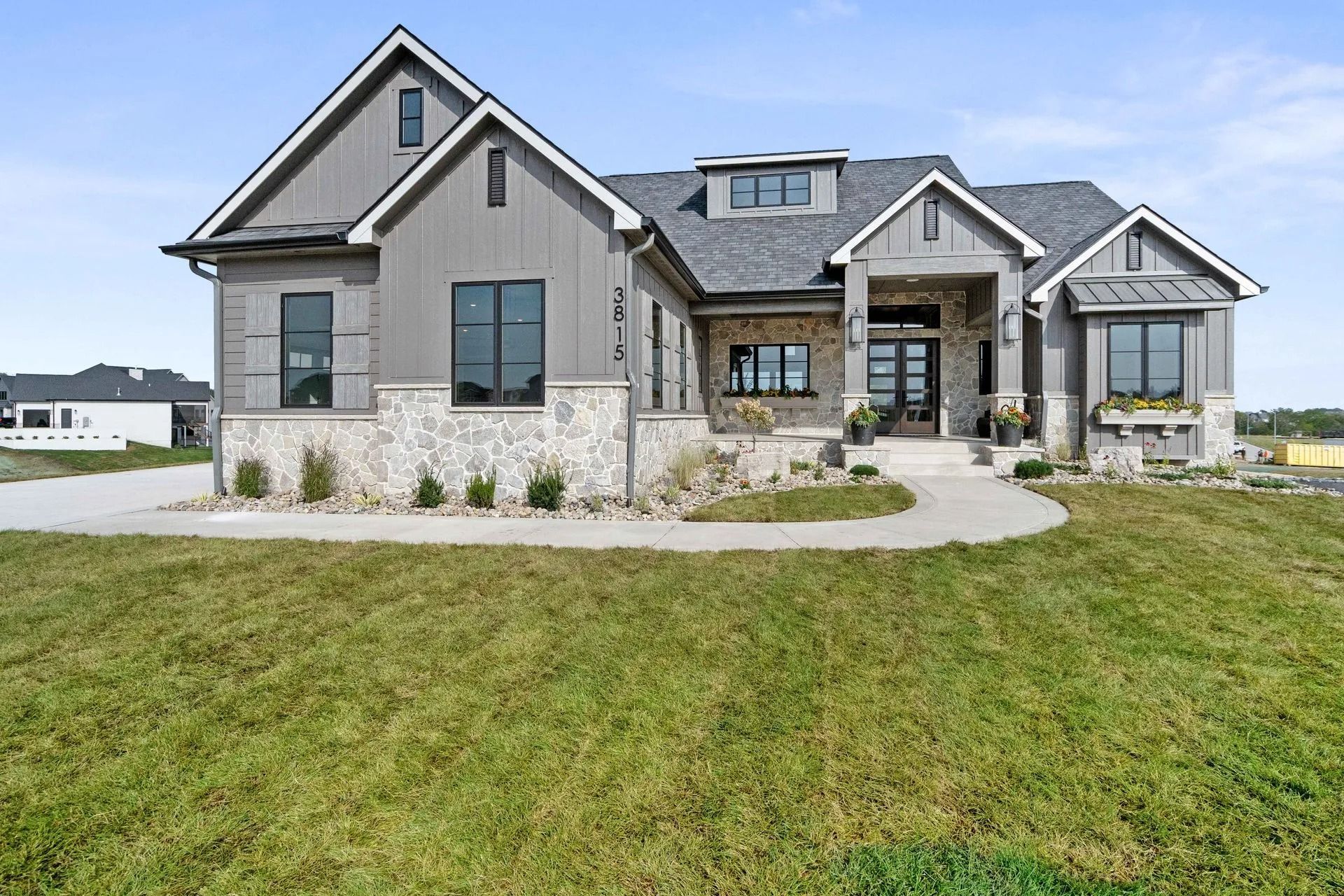 Gray and stone house with dark windows and a pathway.