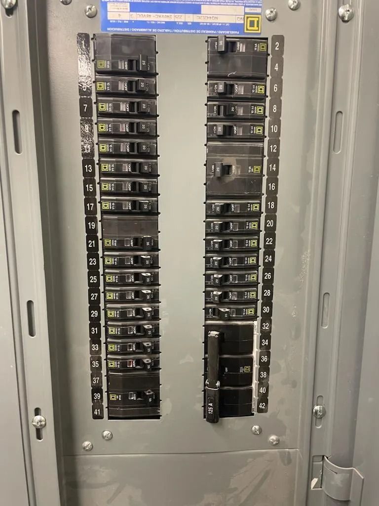 Electrical circuit breaker panel with numerous switches in a metal enclosure.