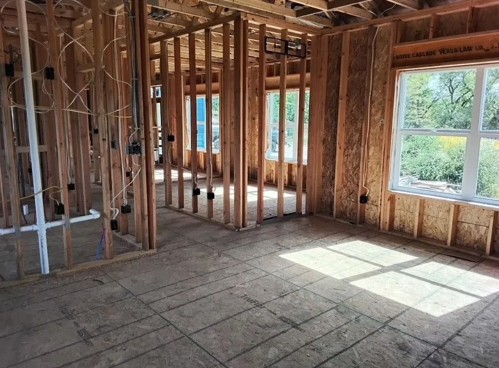 Interior of a house under construction. Wooden framing, exposed studs, and windows.